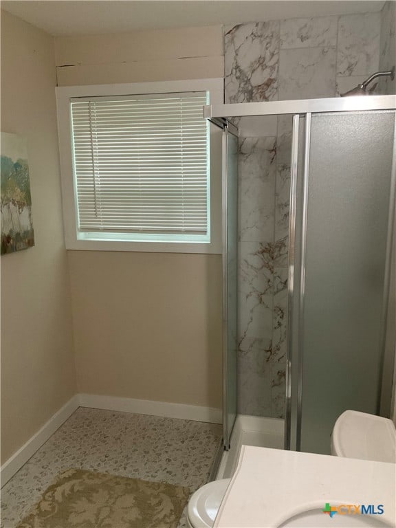 bathroom with vanity, toilet, and a shower with door