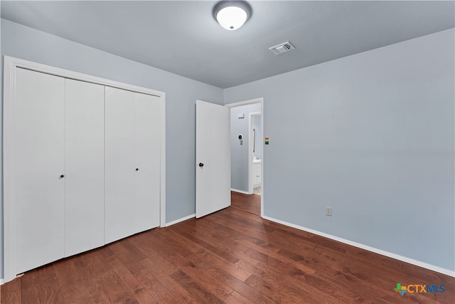 unfurnished bedroom with dark hardwood / wood-style floors and a closet