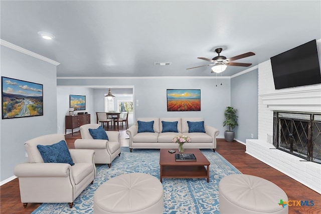 living room featuring ceiling fan, hardwood / wood-style floors, crown molding, and a fireplace