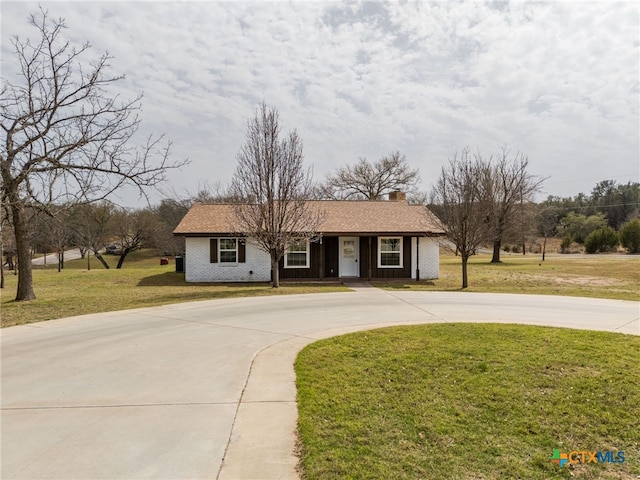 view of front of house featuring brick siding, concrete driveway, and a front yard