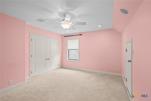 unfurnished bedroom featuring ceiling fan, a closet, light colored carpet, and vaulted ceiling