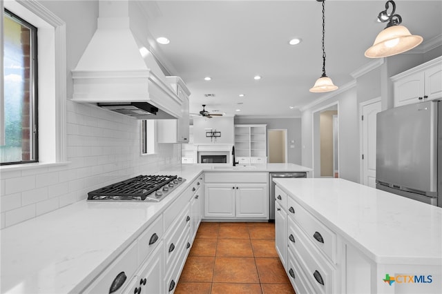 kitchen featuring pendant lighting, white cabinets, stainless steel appliances, and custom range hood