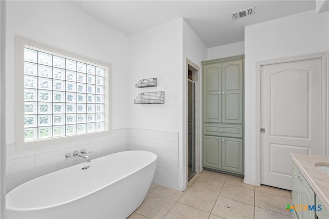 26 Cotswold Ln, Victoria, TX 77904 - bathroom featuring a freestanding tub, vanity, tile patterned flooring, a stall shower, and tile walls