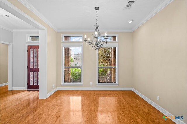 unfurnished dining area with light wood-type flooring, an inviting chandelier, and ornamental molding