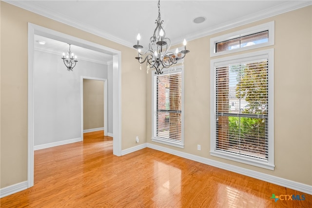 unfurnished dining area with light hardwood / wood-style floors, an inviting chandelier, and crown molding