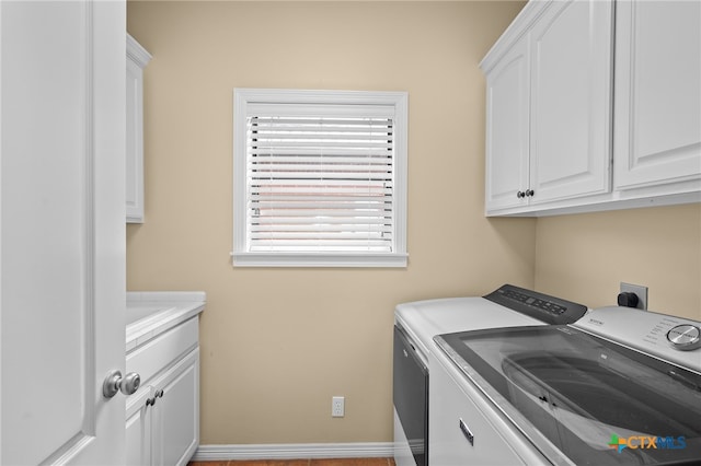 washroom featuring cabinets, light hardwood / wood-style floors, and washing machine and clothes dryer