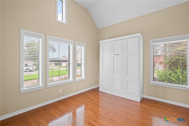 unfurnished bedroom featuring a closet, light hardwood / wood-style floors, and vaulted ceiling