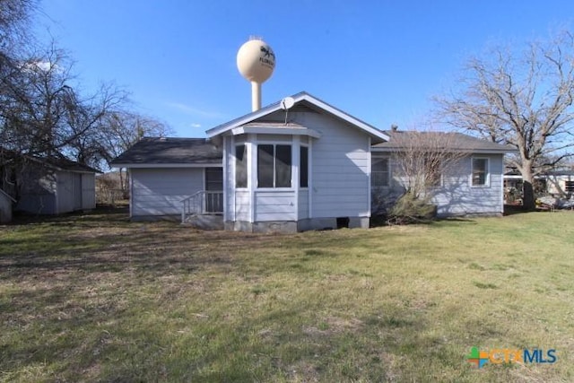 rear view of house featuring an outbuilding, a lawn, and a shed