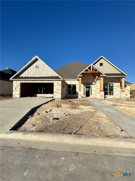 property in mid-construction with board and batten siding, stone siding, driveway, and an attached garage