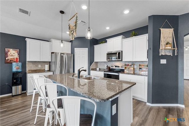 kitchen with visible vents, a breakfast bar area, stainless steel appliances, and a sink