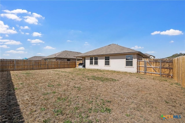 rear view of house featuring a lawn and a fenced backyard