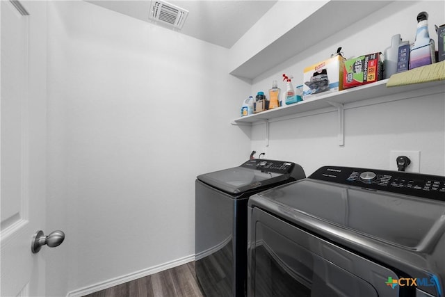 clothes washing area with visible vents, dark wood-style floors, baseboards, laundry area, and washing machine and clothes dryer