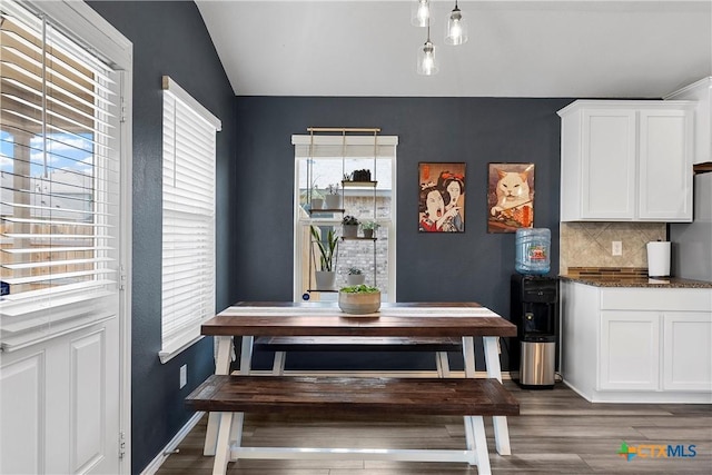 dining space with baseboards, dark wood-style floors, and vaulted ceiling