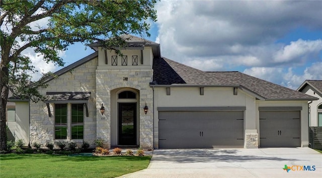 view of front of home with an attached garage, a shingled roof, concrete driveway, stone siding, and stucco siding