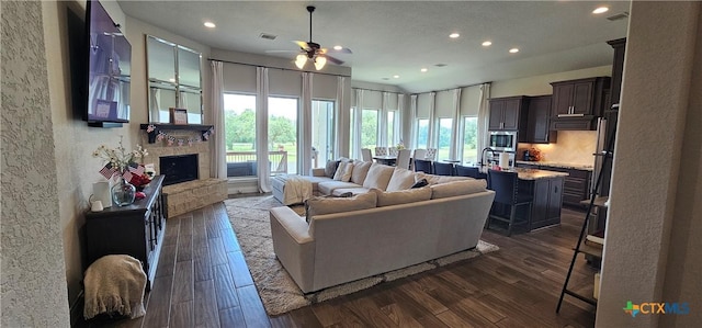 633 Vale Ct, New Braunfels, TX 78132 - living room with ceiling fan, recessed lighting, dark wood-type flooring, a textured wall, and a stone fireplace