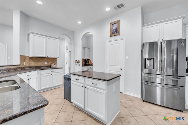 kitchen with white cabinets, light tile patterned floors, stainless steel fridge with ice dispenser, and backsplash