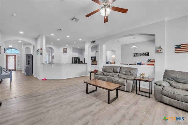 living room with visible vents, light wood-style flooring, a ceiling fan, recessed lighting, and arched walkways