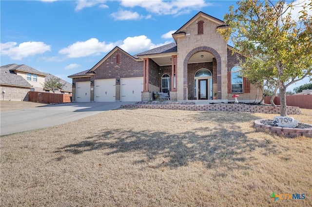 view of front of house featuring stone siding, brick siding, an attached garage, and fence