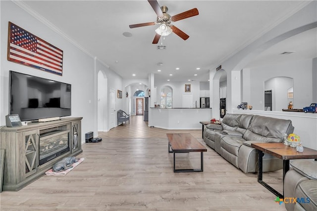 living area with visible vents, ornamental molding, recessed lighting, light wood-style floors, and arched walkways