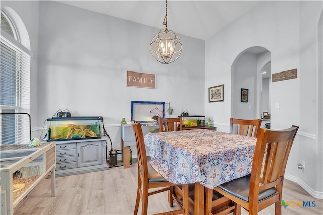 dining area with an inviting chandelier, wood finished floors, arched walkways, and baseboards