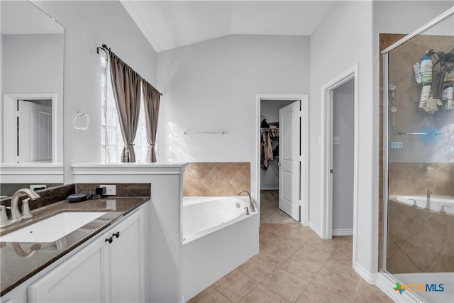 bathroom with a stall shower, a spacious closet, a bath, vanity, and vaulted ceiling