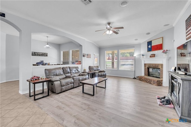 living area with visible vents, light wood-style floors, a fireplace, and crown molding