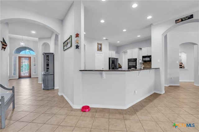 kitchen featuring black appliances, a kitchen breakfast bar, white cabinetry, recessed lighting, and light tile patterned flooring