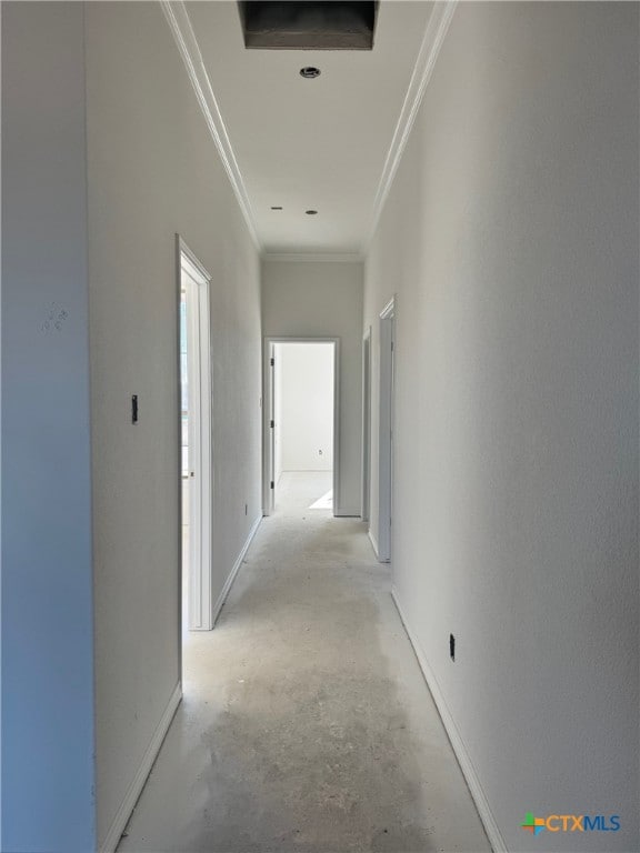 hall with ornamental molding, baseboards, and unfinished concrete floors