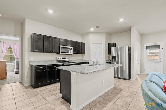 kitchen with visible vents, a sink, light tile patterned floors, stainless steel appliances, and dark cabinets