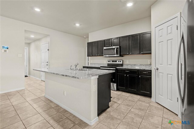 kitchen featuring a sink, stainless steel appliances, dark cabinets, and light tile patterned flooring