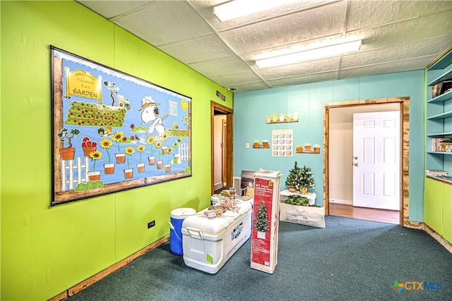 game room with a drop ceiling and dark colored carpet