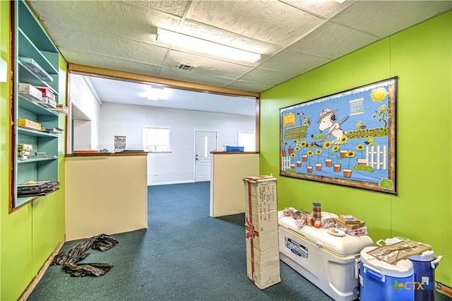 interior space featuring dark carpet and a drop ceiling