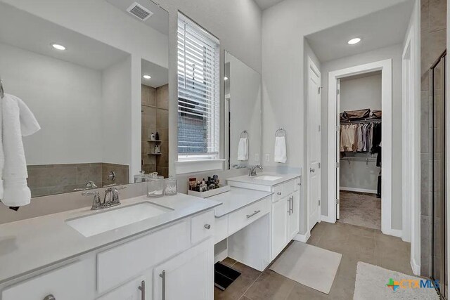 full bath featuring double vanity, a stall shower, visible vents, and a sink