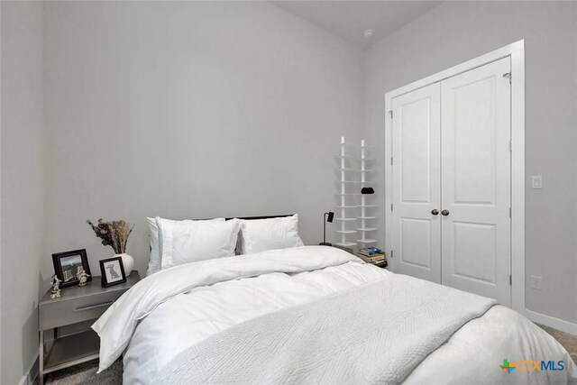 carpeted bedroom featuring a closet and baseboards