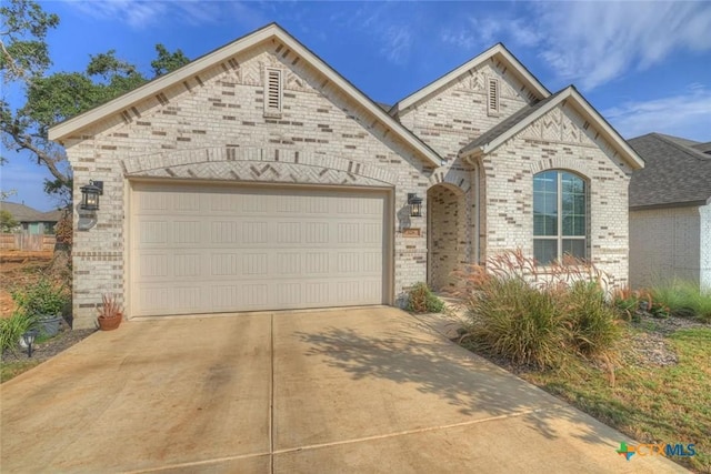 view of front of home with driveway, brick siding, and an attached garage