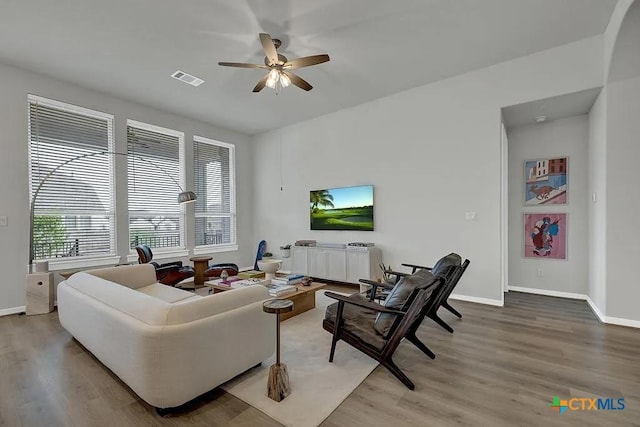 living room featuring visible vents, baseboards, light wood-style flooring, and a ceiling fan