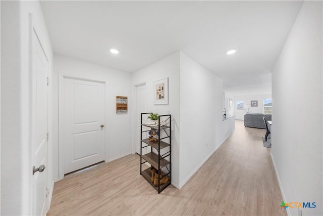 corridor featuring light wood finished floors, baseboards, and recessed lighting
