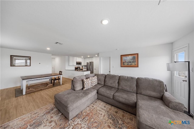 living area with light wood-style flooring, visible vents, and recessed lighting