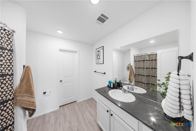 bathroom featuring baseboards, vanity, visible vents, and wood finished floors