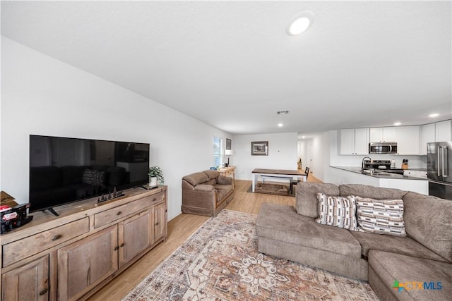 living room with recessed lighting, visible vents, and light wood-type flooring
