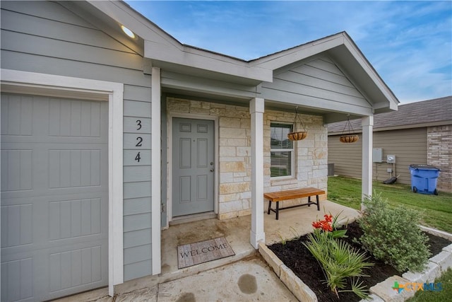 doorway to property with stone siding, a porch, and a garage