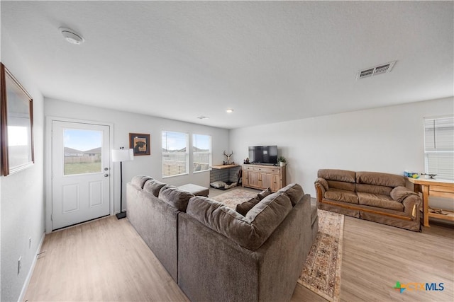 living room with light wood-type flooring, baseboards, and visible vents