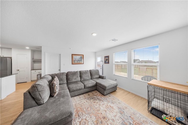 living room featuring light wood-style flooring, visible vents, and recessed lighting
