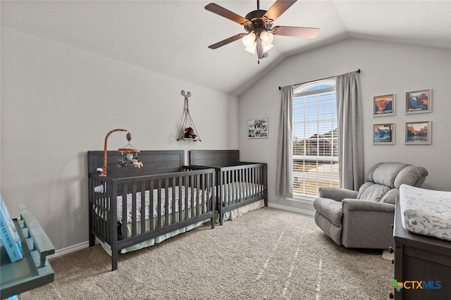 bedroom with a ceiling fan, a nursery area, carpet, baseboards, and vaulted ceiling