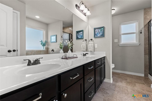 bathroom with a shower stall, toilet, double vanity, and a sink