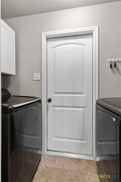 laundry room featuring separate washer and dryer, cabinet space, a textured wall, and a textured ceiling