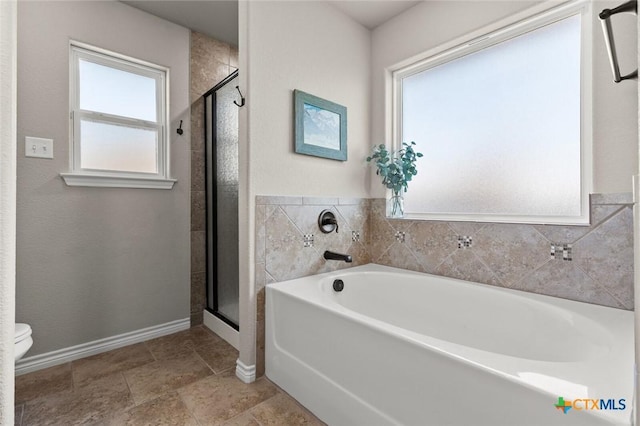 bathroom with a bath, a stall shower, toilet, and baseboards