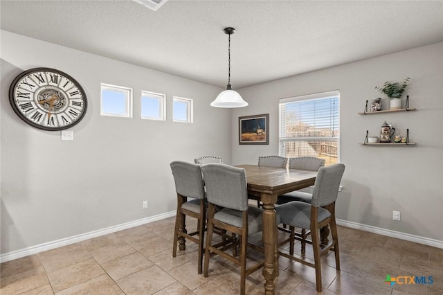 dining area with light tile patterned floors, baseboards, and a textured ceiling