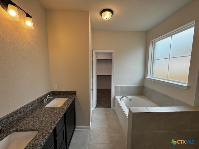 bathroom with vanity, tile patterned floors, and a relaxing tiled tub