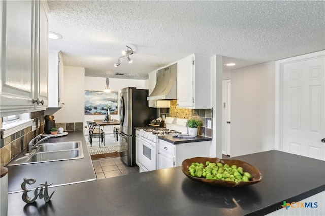 kitchen with a sink, wall chimney exhaust hood, white cabinets, dark countertops, and white range with gas stovetop